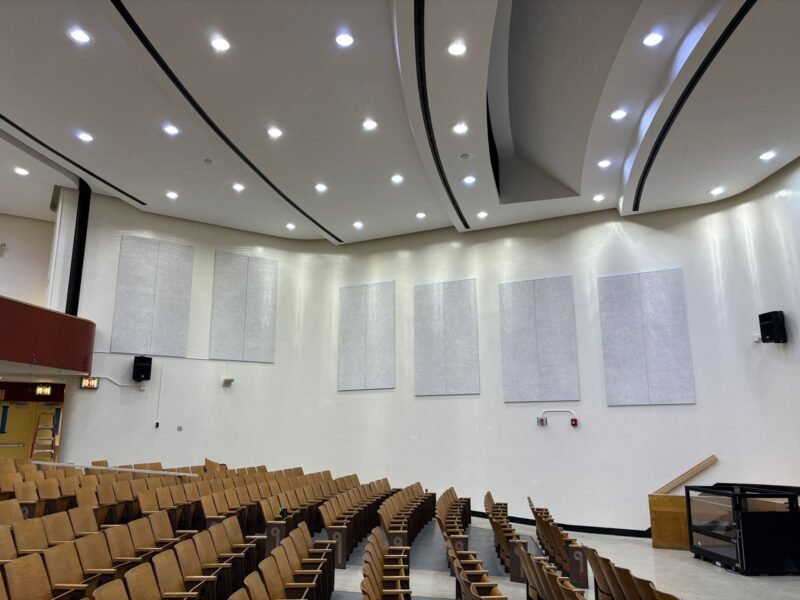 Auditorium with acoustic wall panels, curved ceiling coves and recessed lighting
