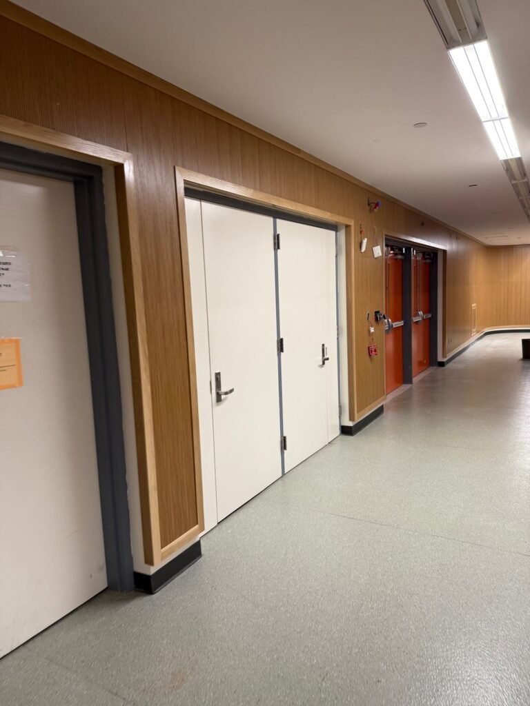 Corridor finished with wood wall paneling, new doors and speckled flooring